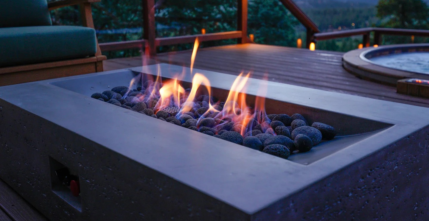 Rectangular concrete fire pit with lava rocks at dusk